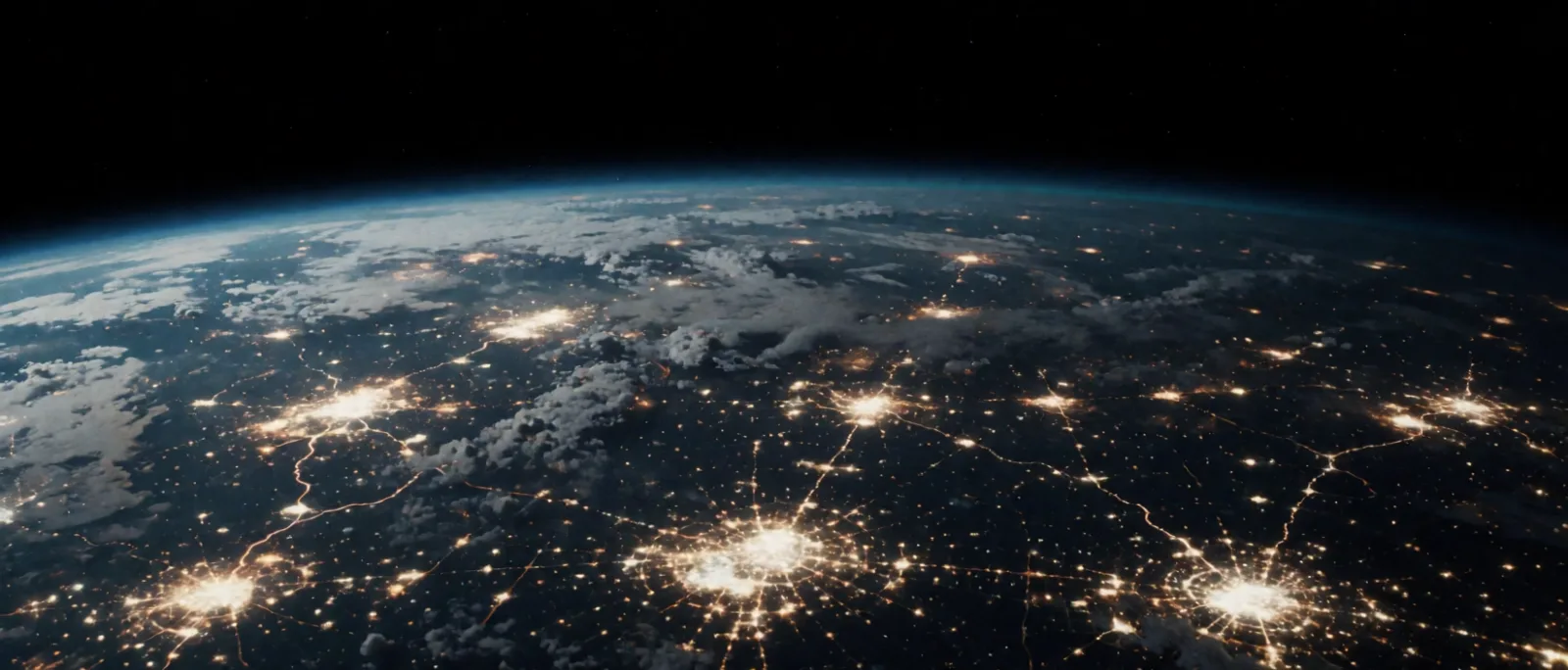 City lights seen from low orbit at night, curving along the dark horizon of the Earth
