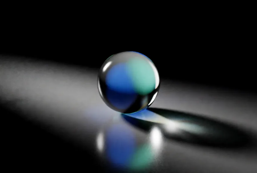 A glass orb reflecting blue and teal light on a dark surface