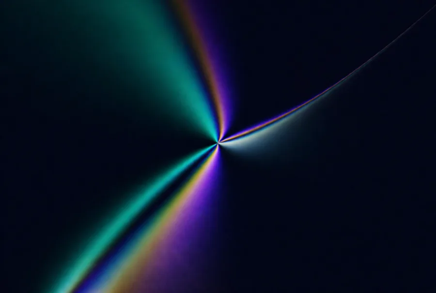 Two beams crossing at a single bright point and splitting into bands of teal and violet as they pass a curved glass edge