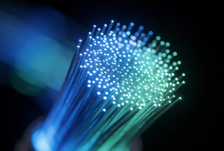 A macro of glowing fibre-optic strands in teal and blue