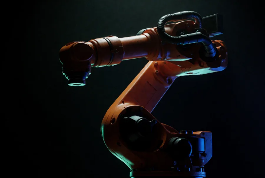 An orange industrial robot arm rim-lit in teal and blue
